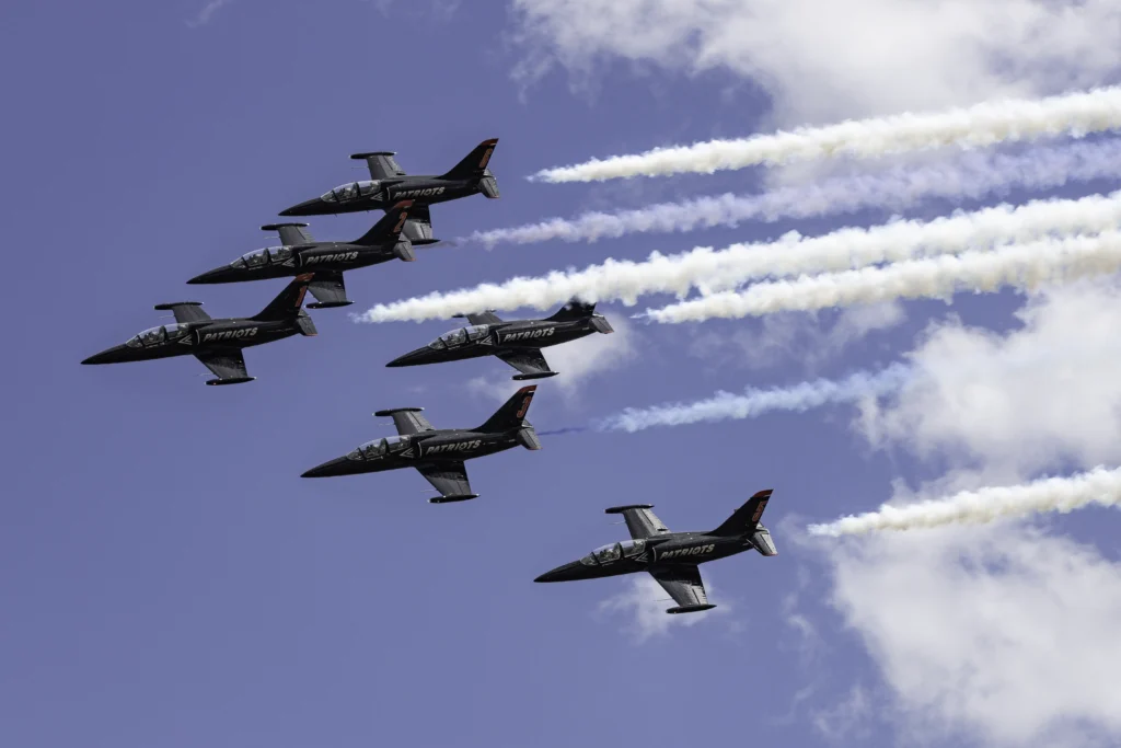 Six Patriots Jet Team Aero L-39 Albatros jets fly in close formation with white smoke trails against a blue sky during SkyFest 2026 at Fairchild Air Force Base.