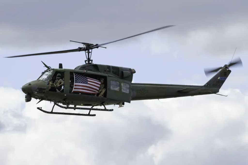 U.S. Air Force SERE School UH-1N Huey helicopter carrying the American flag during the opening ceremonies at the Fairchild AFB SkyFest Air Show.